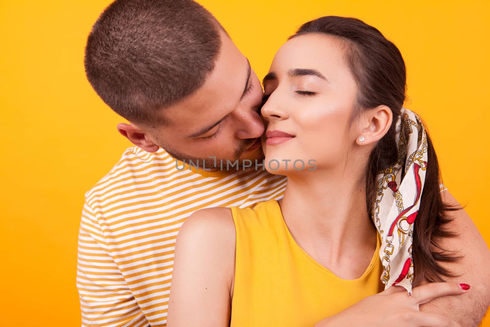 Handsome boyfriend kissing his beautiful girlfriend from behind on her cheek. Relationship goals.