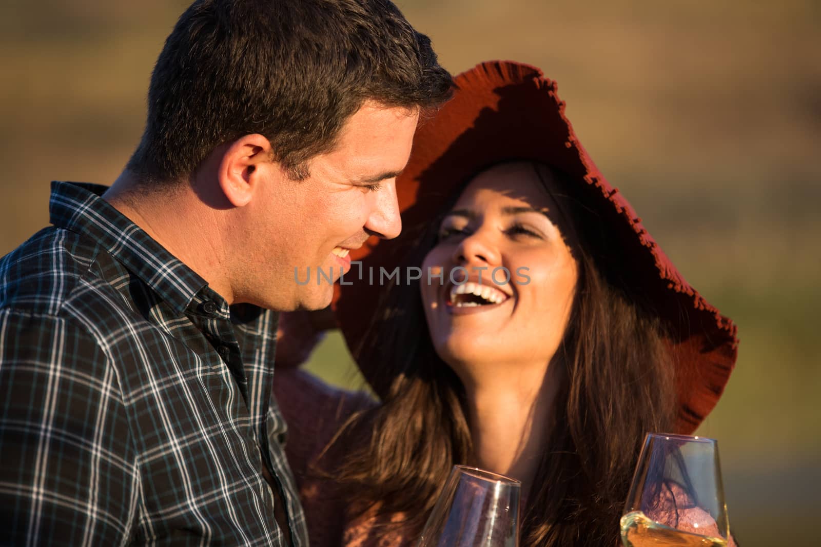 Portrait of couple with a big smile at sunset with lake behind them in the middle of a vineyard.