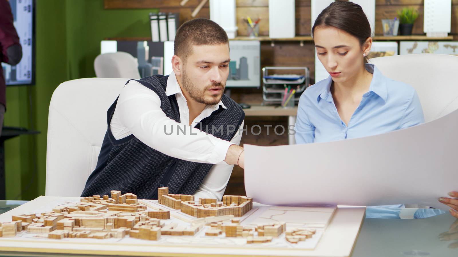 Team of architect holding blue print and working with building models for new town project.