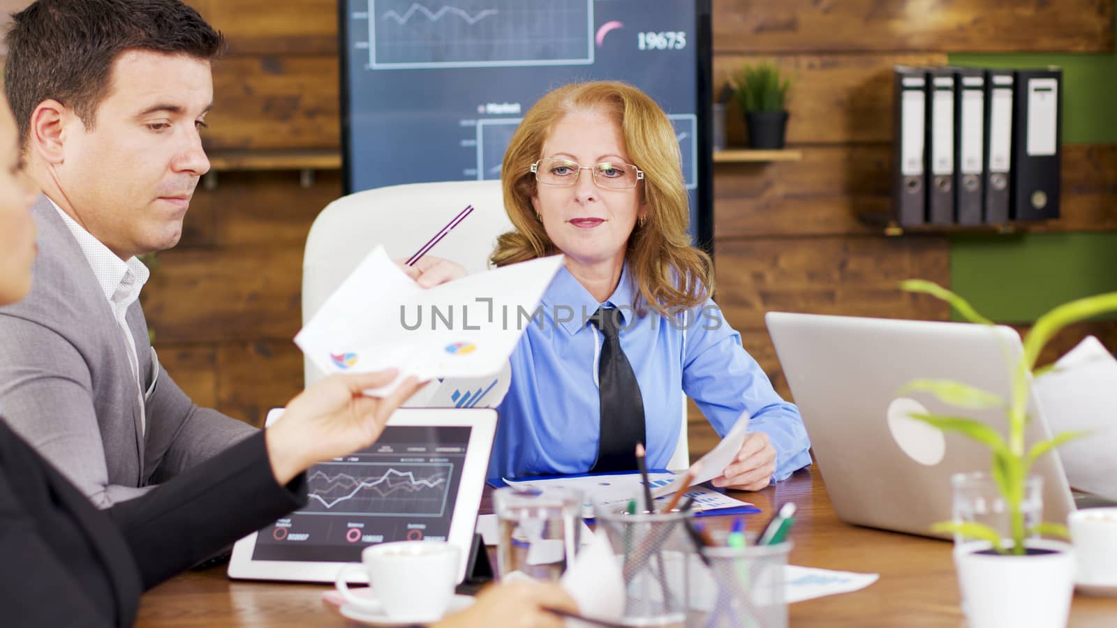Corporate female business trainer discussing financial graph. Investment team in the conference room.