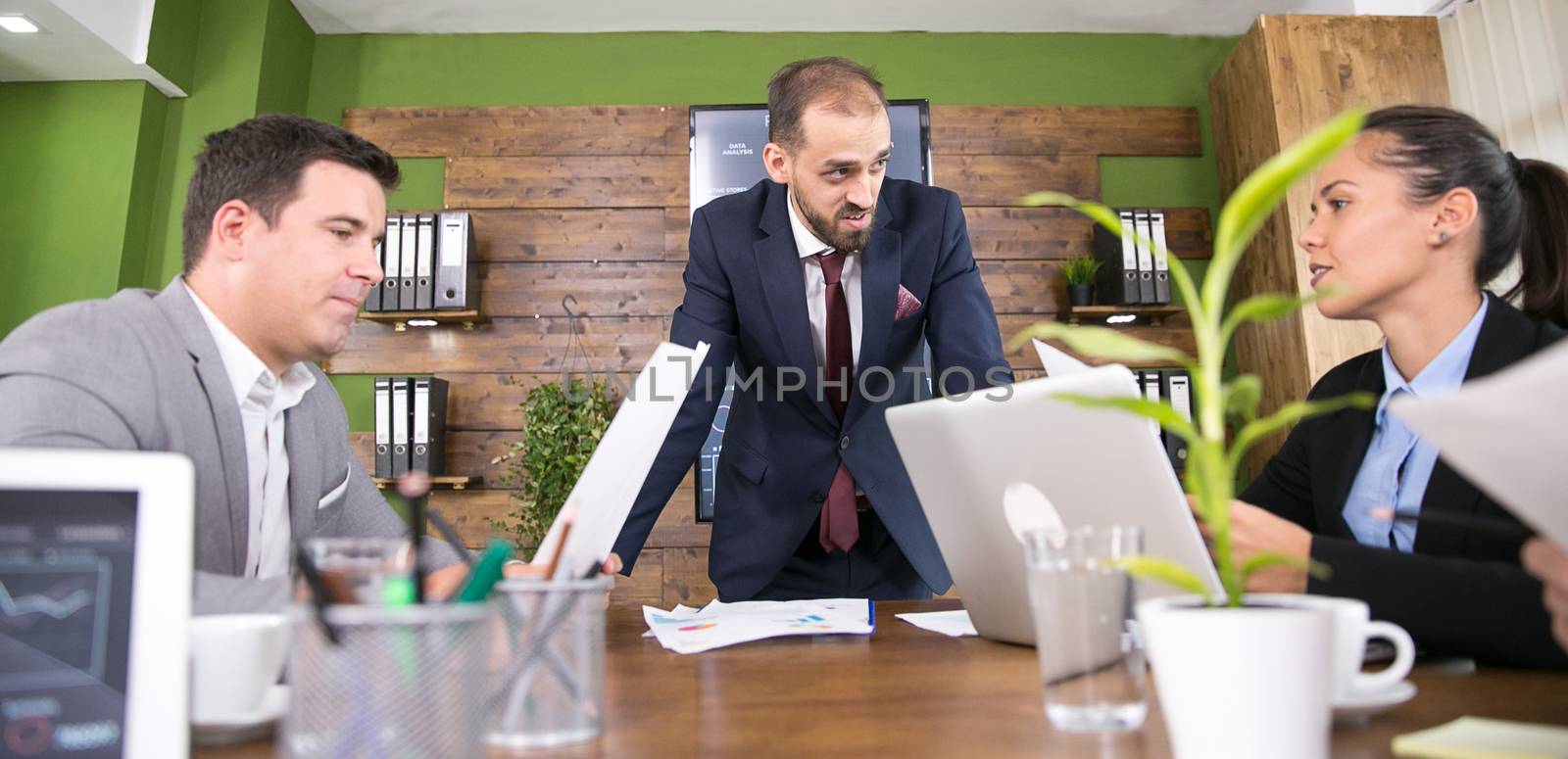 Caucasian businessman in suit discussing with his team in conference room.