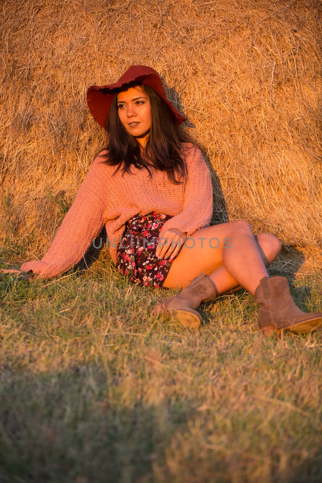 Beautiful young woman with a stylish hat at sunset in a vineyard.