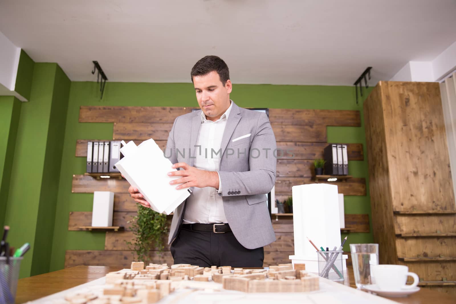 Young architect looking and holding building model in conferene room. Mini town.