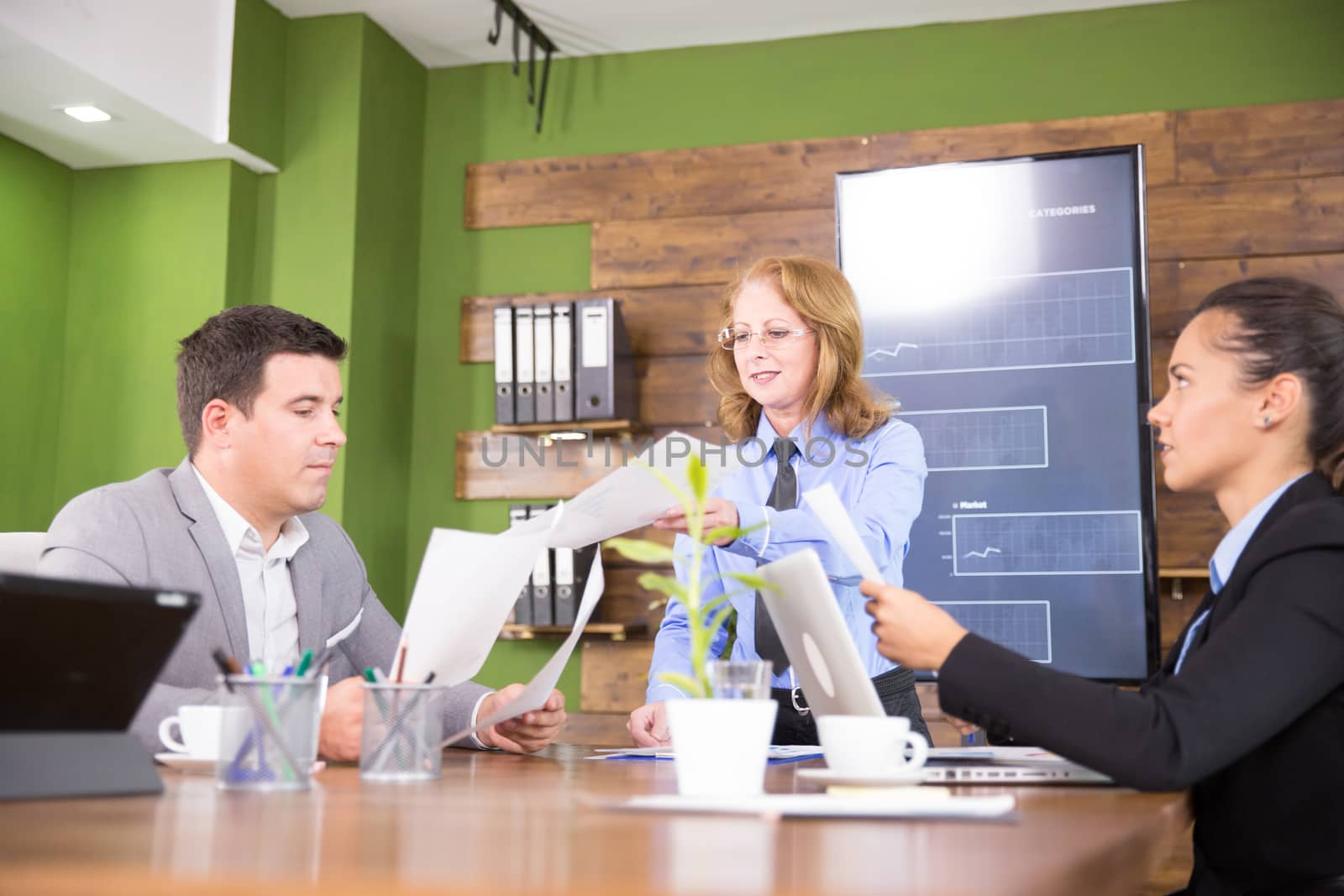 Team of business people having a meeting in a conference room. Businessman holdin charts.