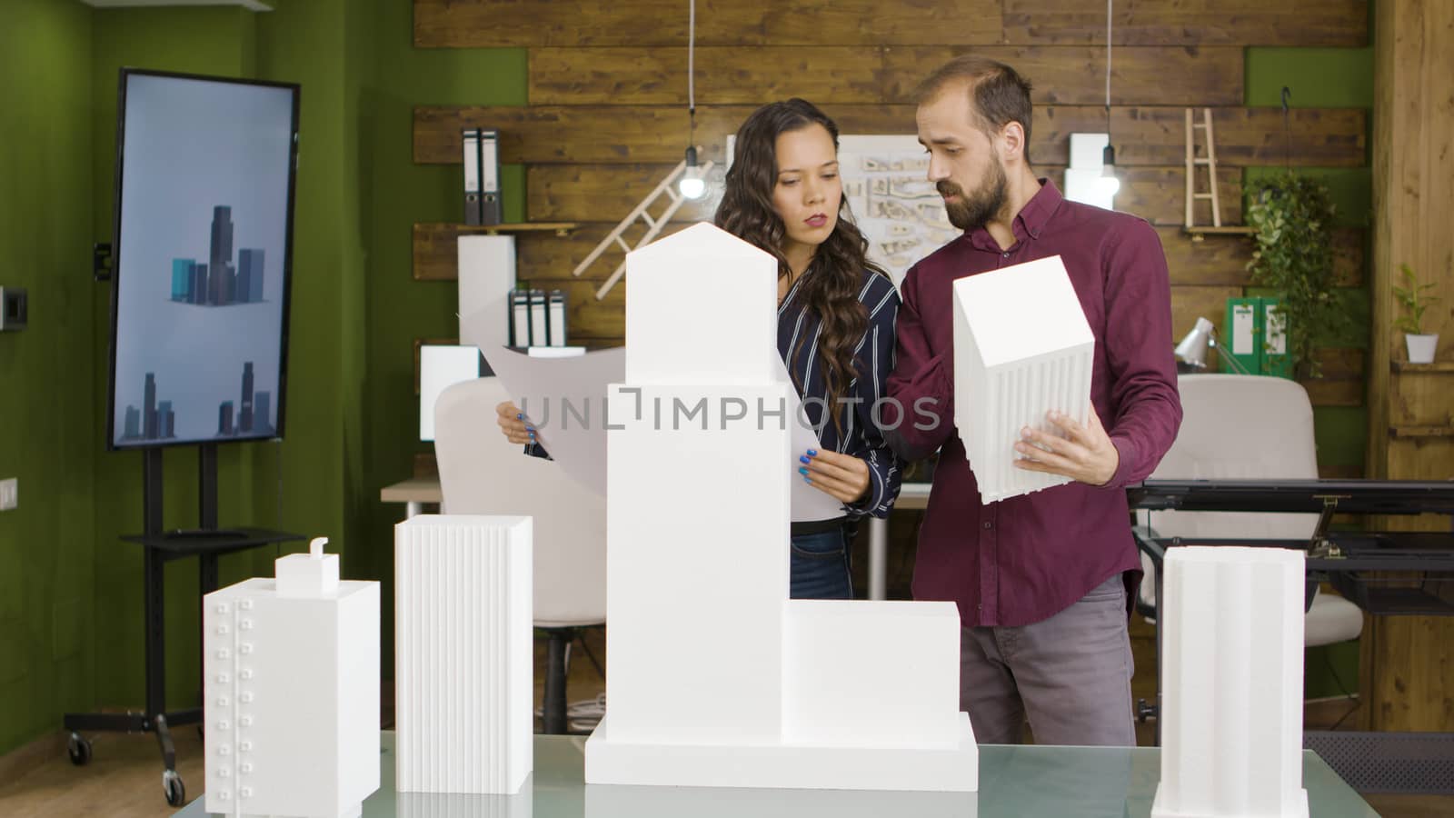 Woman and man architects talking about new project near 3D printed versions of buildings