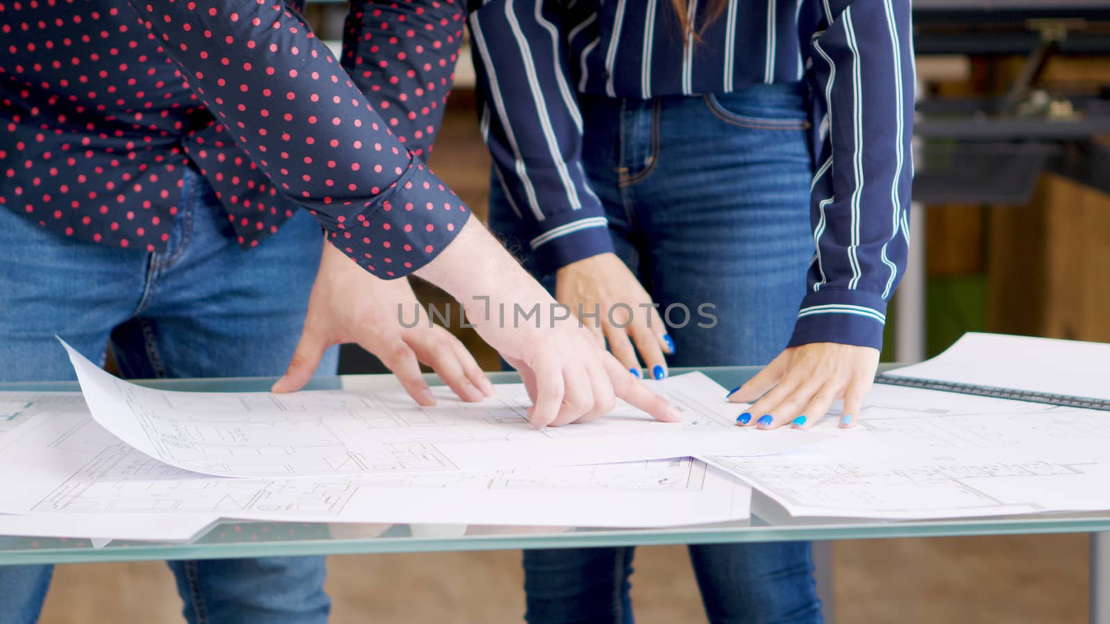 Male architect pointing at something on blueprints near his female colleague