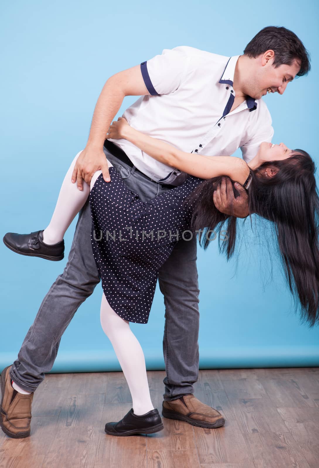 Caucasian boyfriend dancing with his asian girlfriend in studio. Interracial couple.