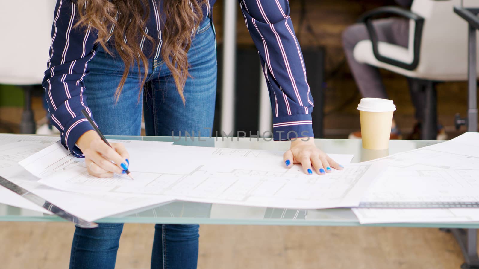 Close up shot of creative designer working on blue prints in modern office