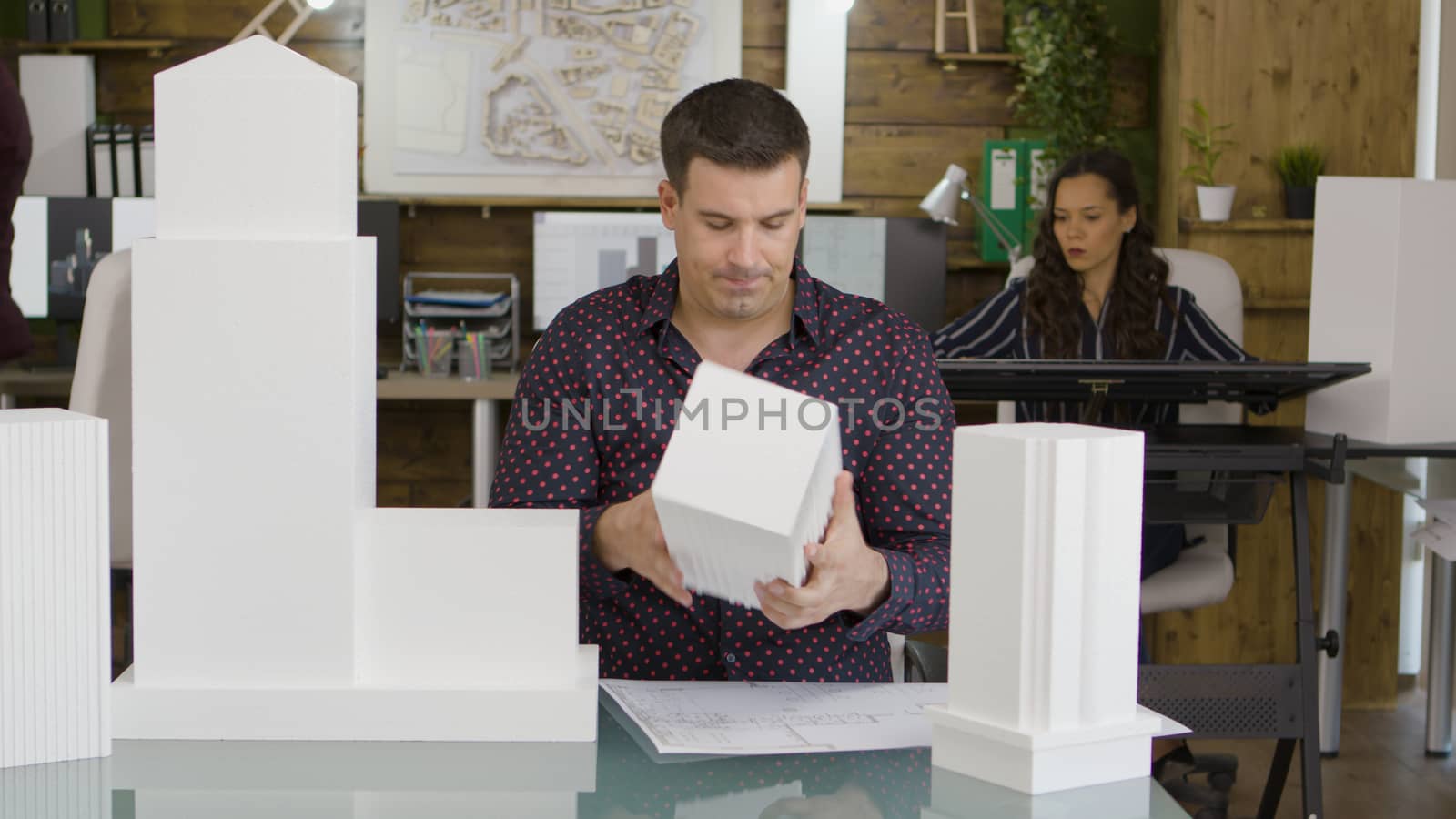 Male architect looking at a 3D printed model of a real business office building