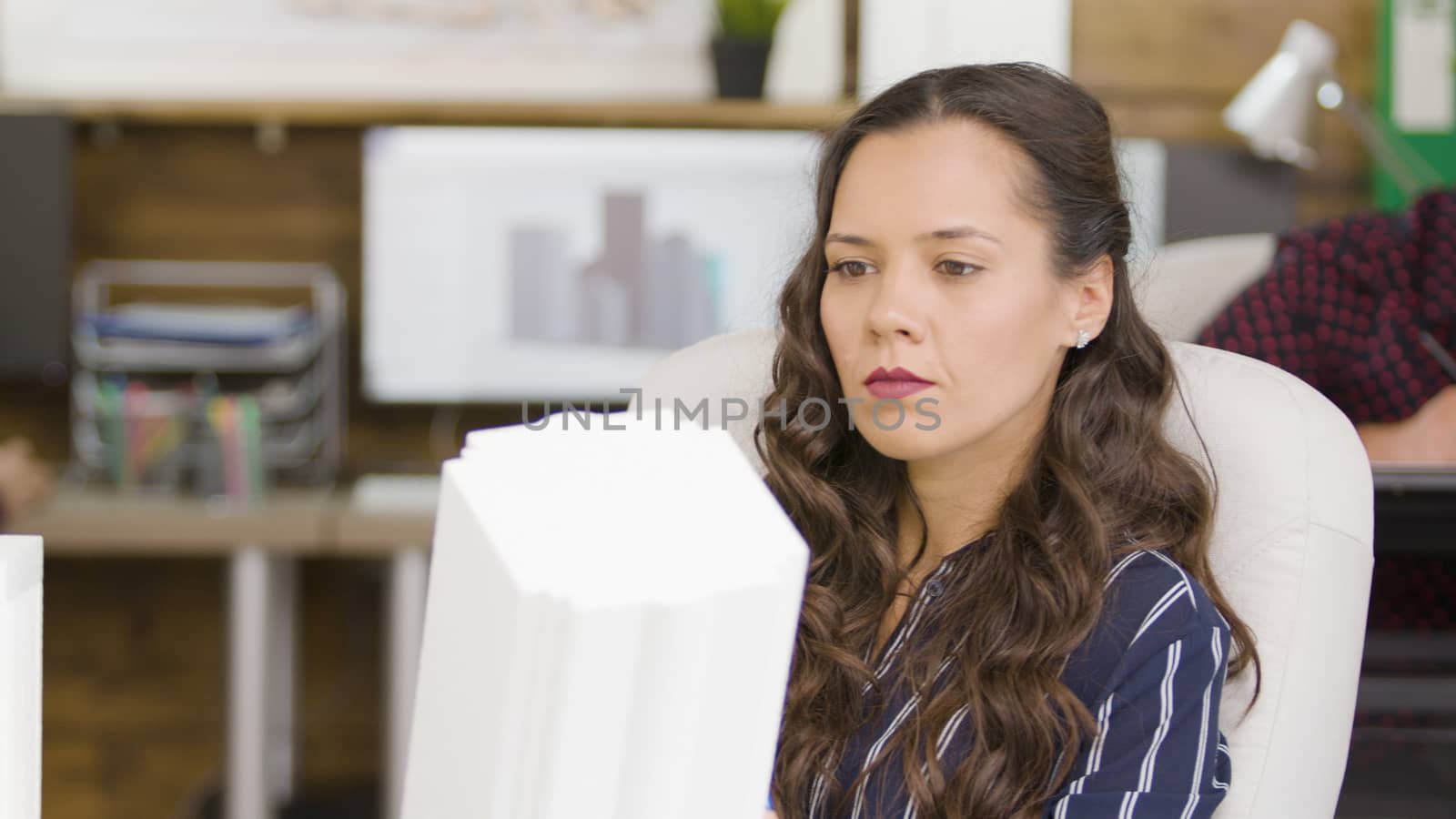 Beautiful caucasian architec looking at a 3D printed building model in modern office
