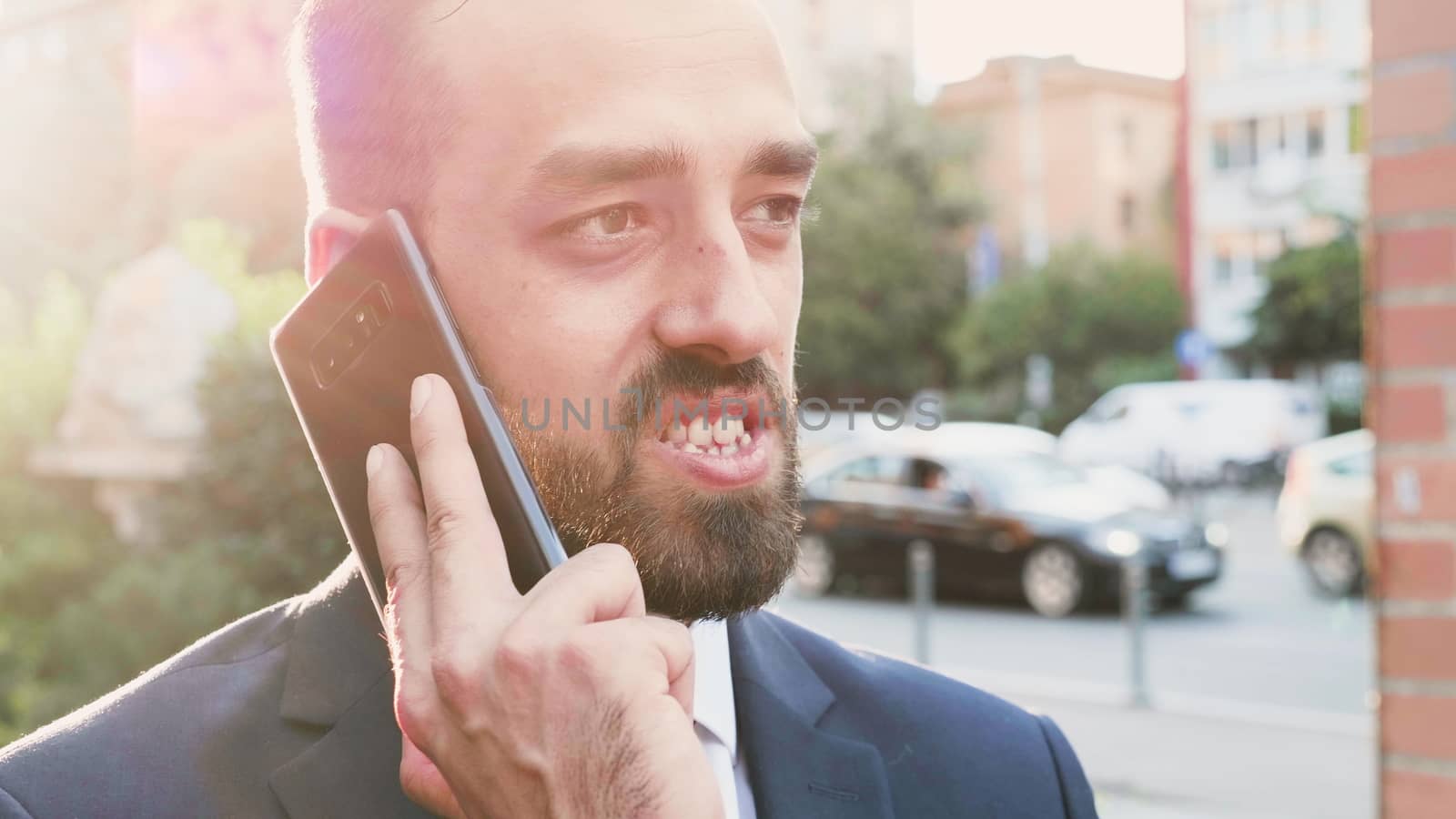 Portrait of business person talking on the phone with the sun behind him in the city creating beautiful lens flares. Slow motion shot