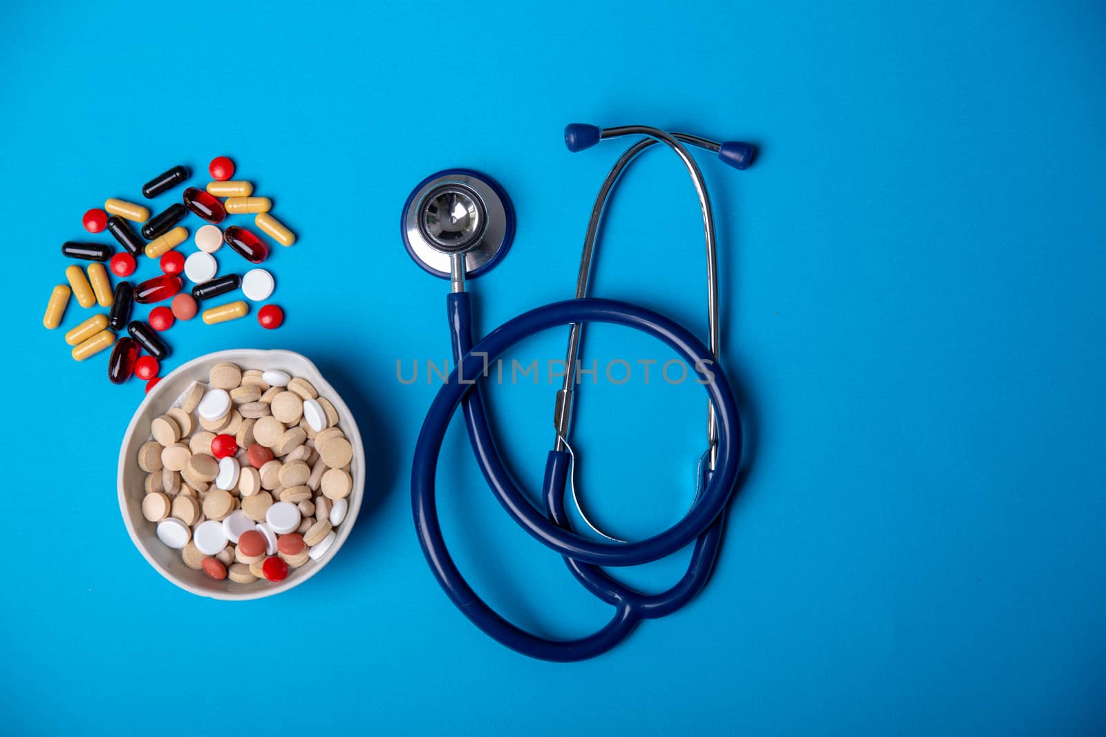 Top view with a stethoscope and pills on a blue background. Close up and copy space