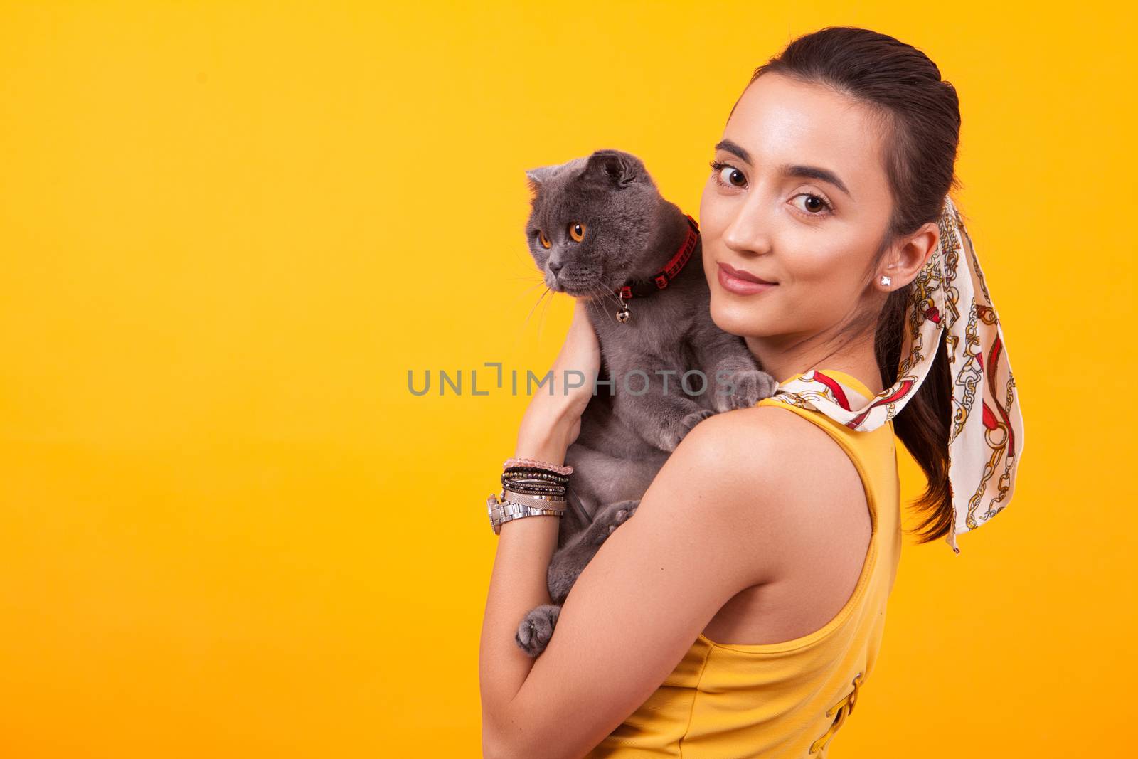 Portrait of beautiful girl holding adorable cat and looking at the camera.