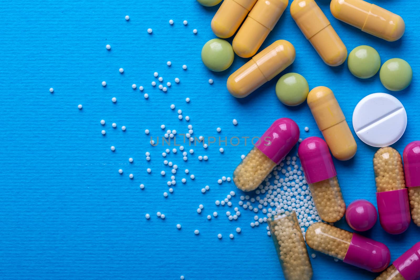 Top view with white pills and yellow capsules and purple and green pills. Copy space and macro
