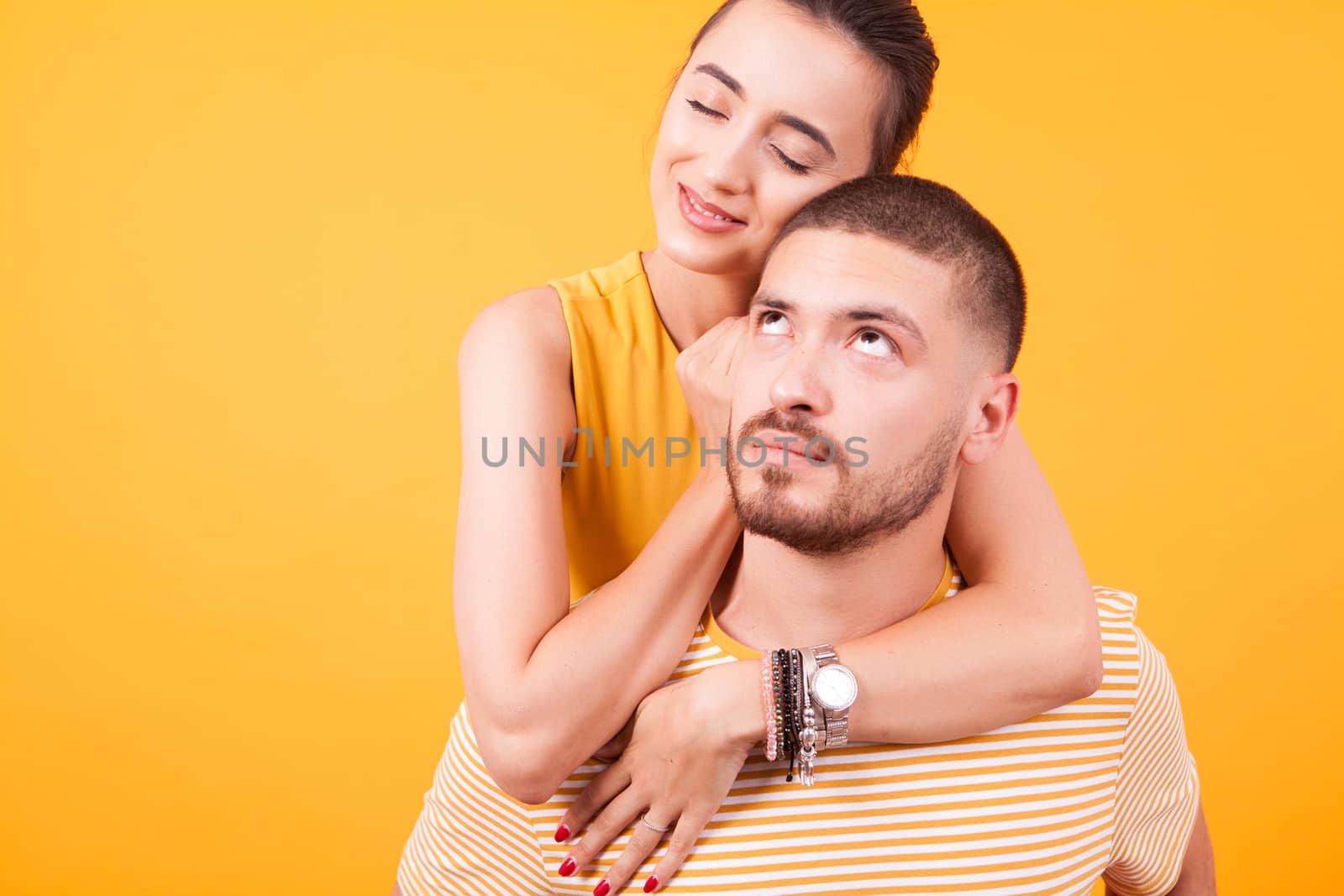 Girlfriend showing love to her boyfriend while he's peggybacking her. Happy young couple.