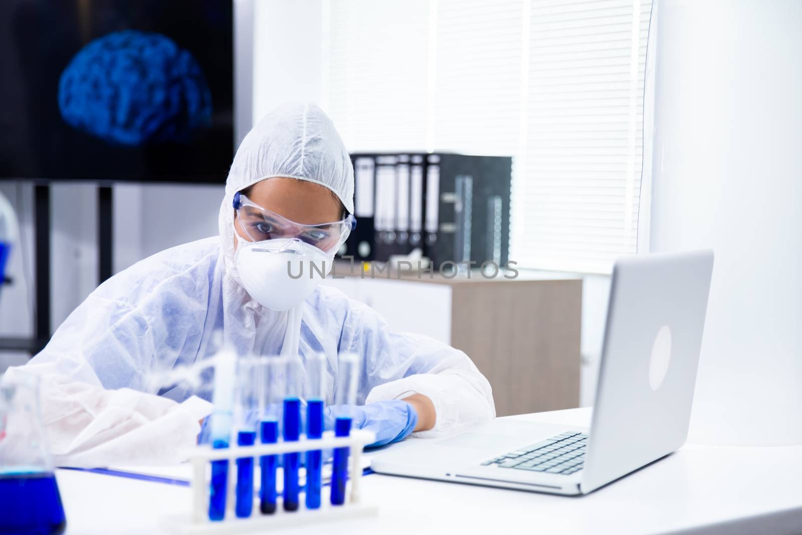 The researcher looks at a tube holder with a blue liquid in them. High-end laboratory