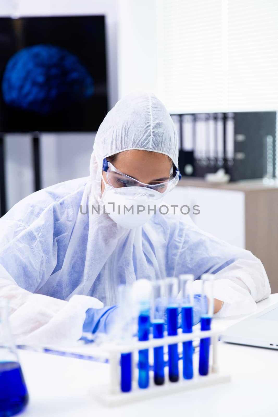 Full-fledged female chemist writes something on a sheet and faces a test tube from which smoke comes out