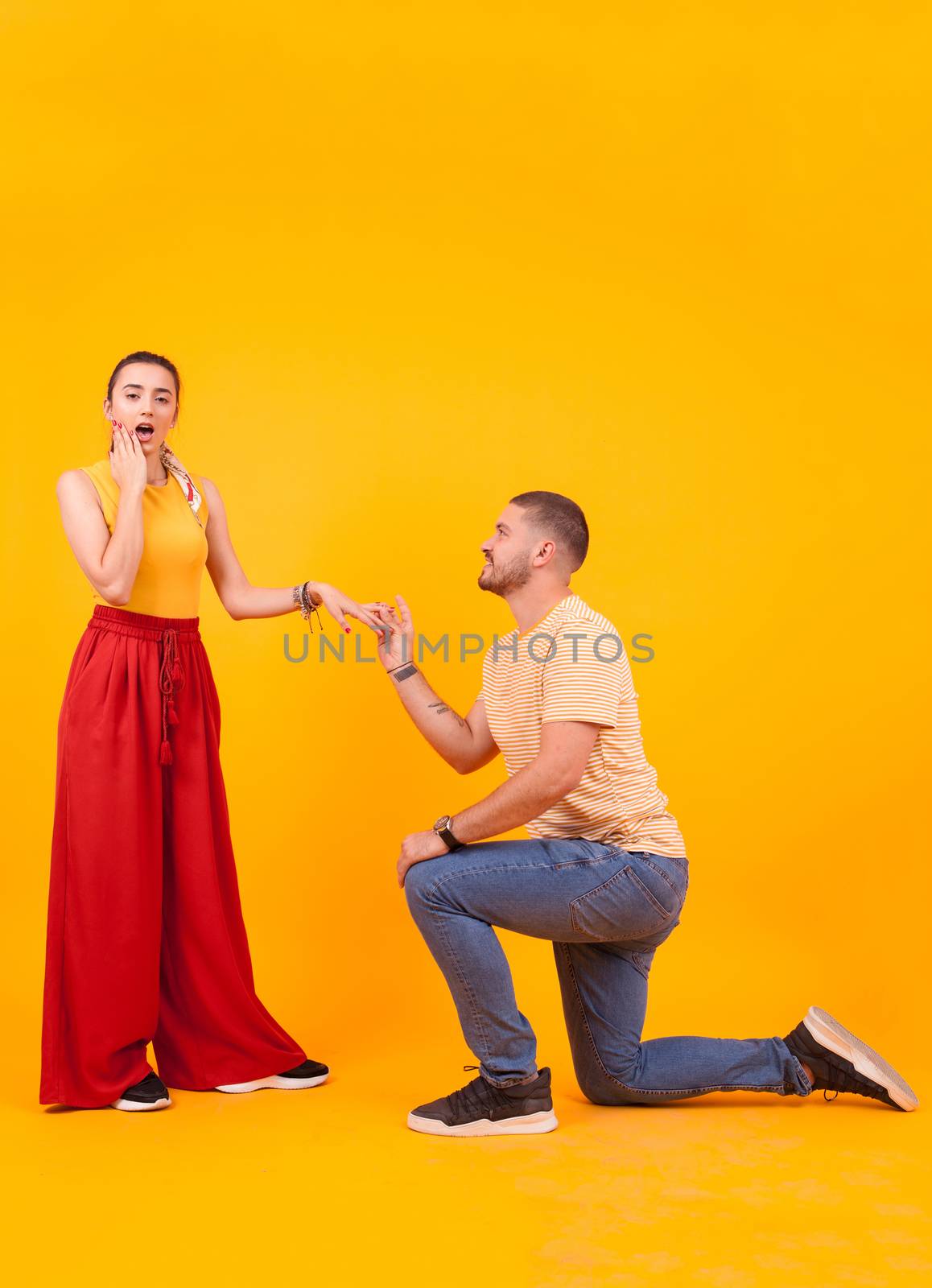 Boyfriend down on his knees asking girlfriend to marry him. Shocked girlfriend.