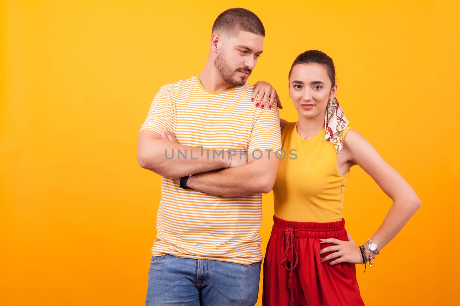 Handsome young man with arms crossed looking at his beautiful girlfriend. Beautiful couple.