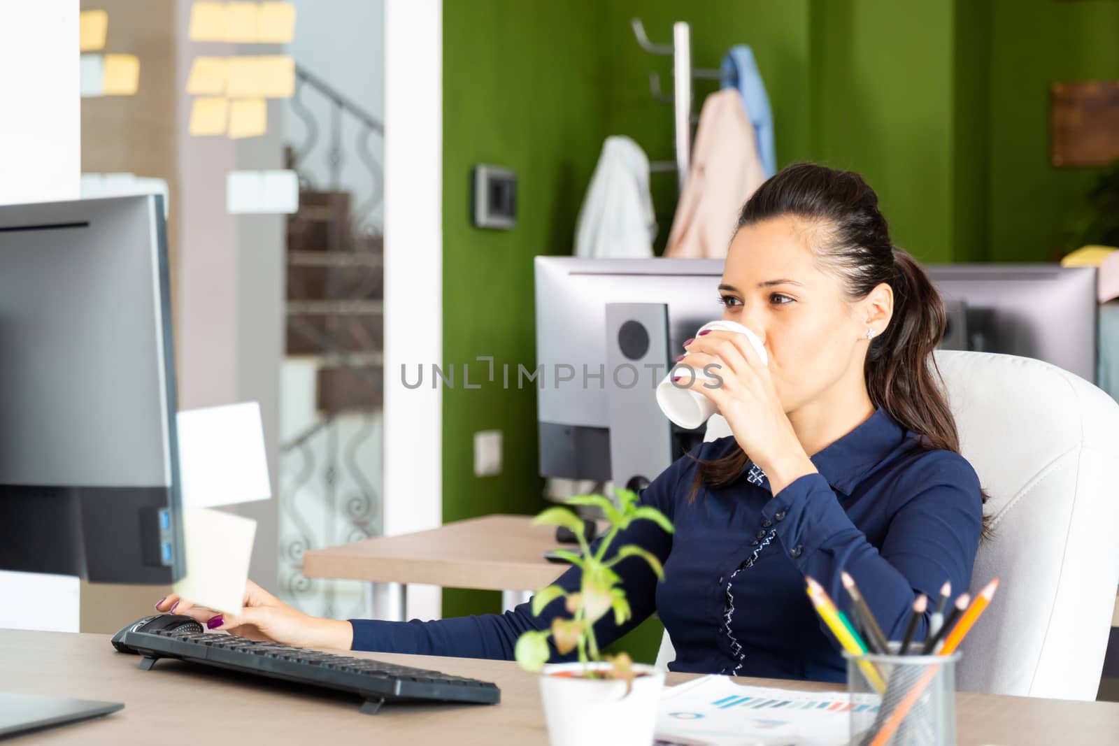 Young girl drinks coffee at the office.Stand on the chair