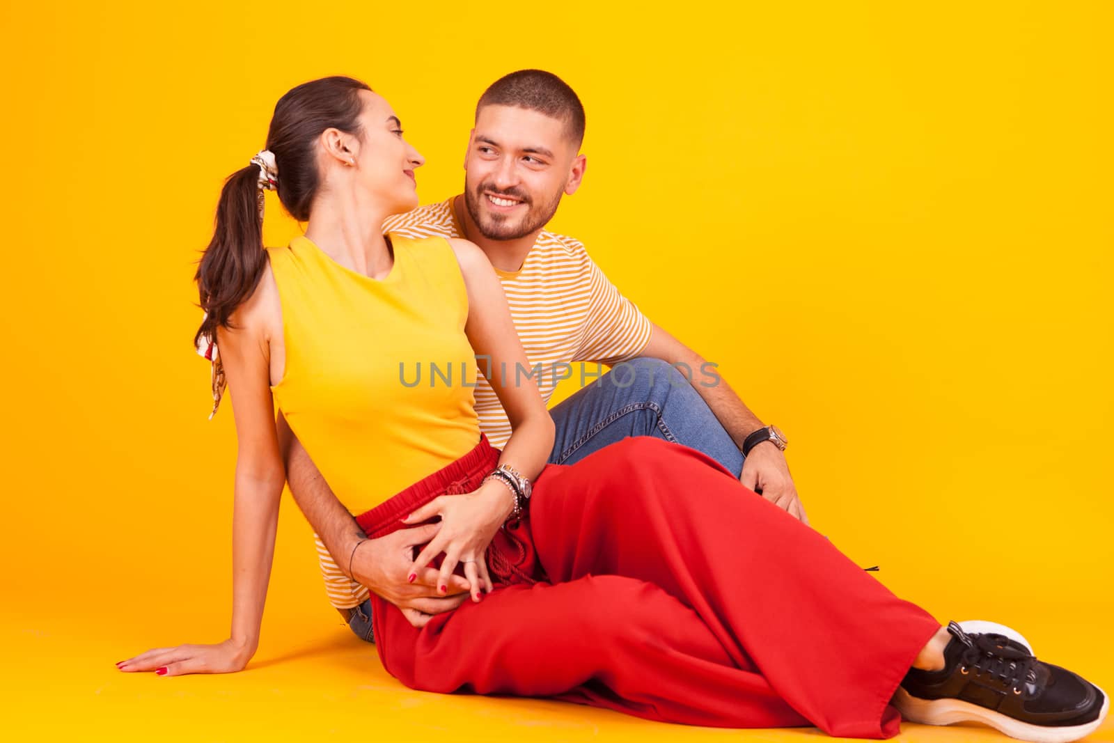 Beautiful young couple holding hands and looking at each other in studio. Joyful couple.