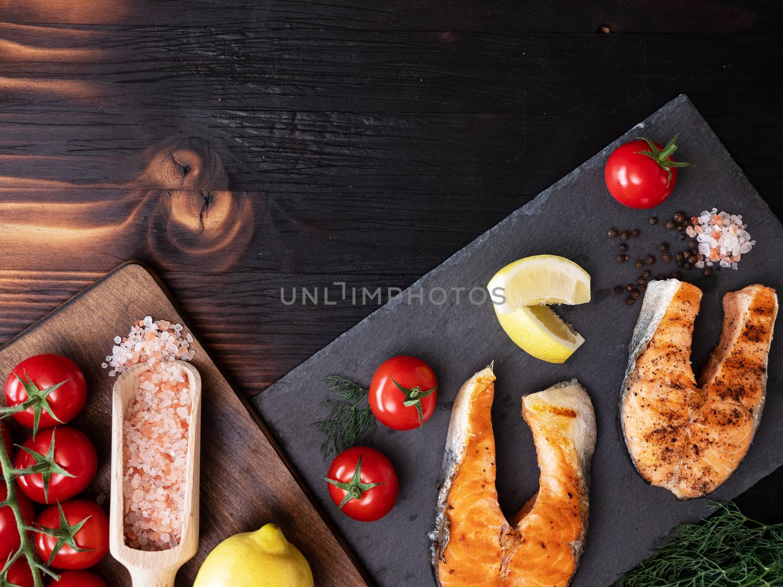 Top view of trays on which salmon and tomato rings are arranged. Wooden table