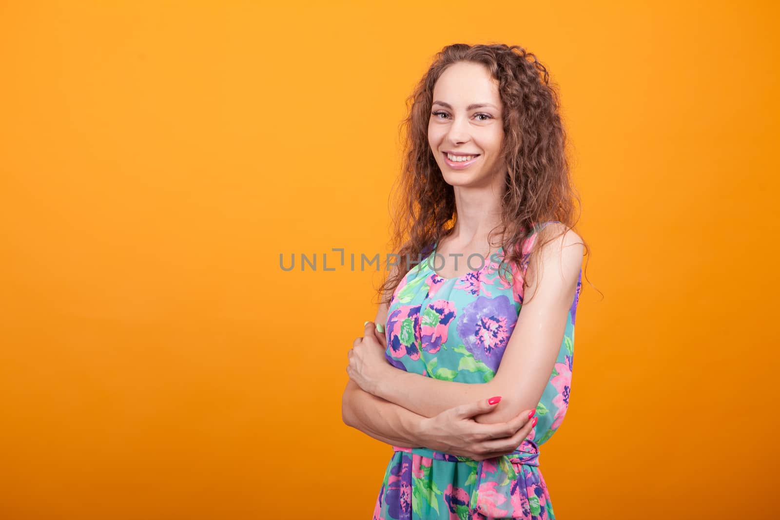 Side view studio shot of cheerful woman with hands crossed and big natural smile.