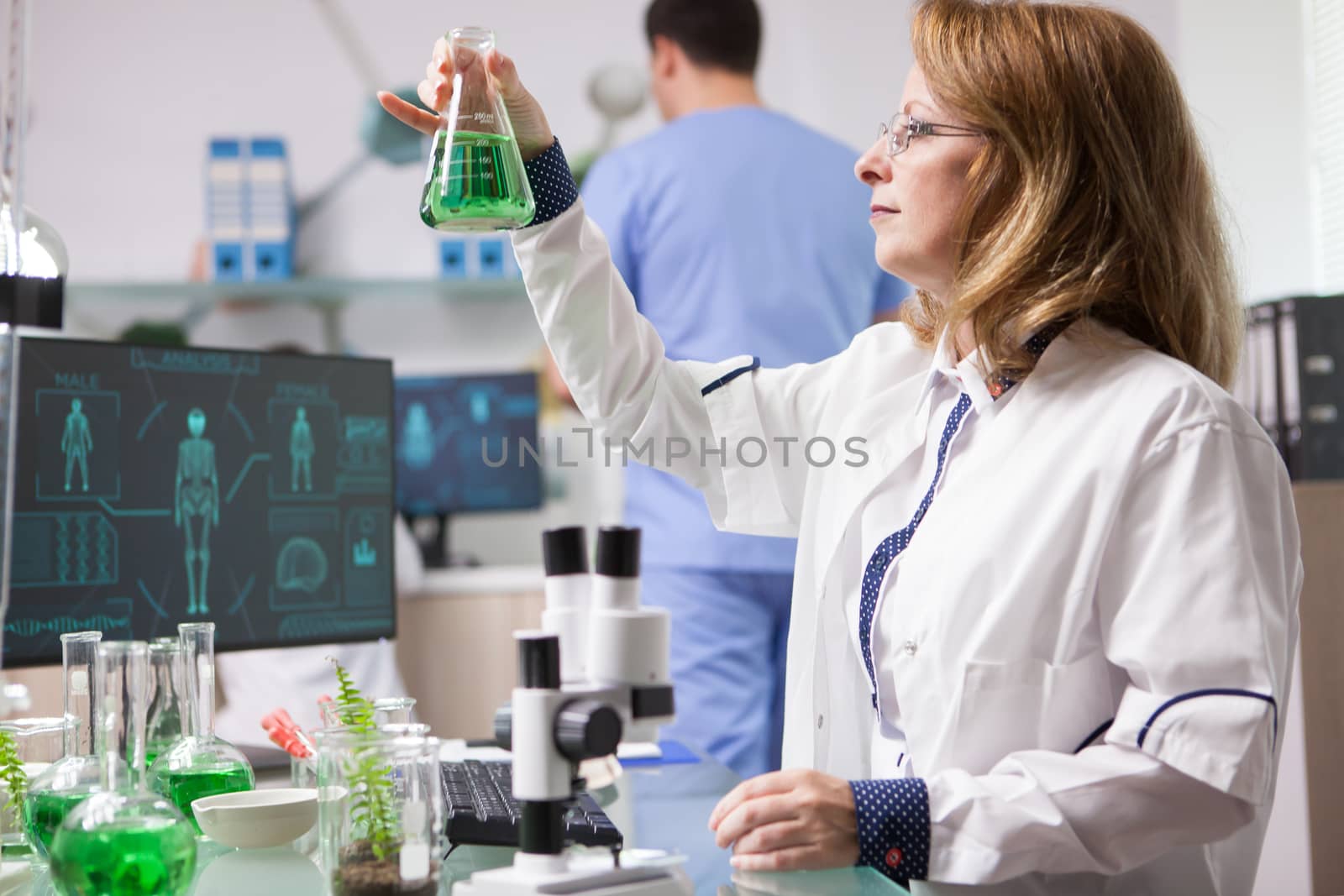 Female biologist holding and analysing a solution for healthy vegetables. Caucasian scientist. Biologist in research lab.