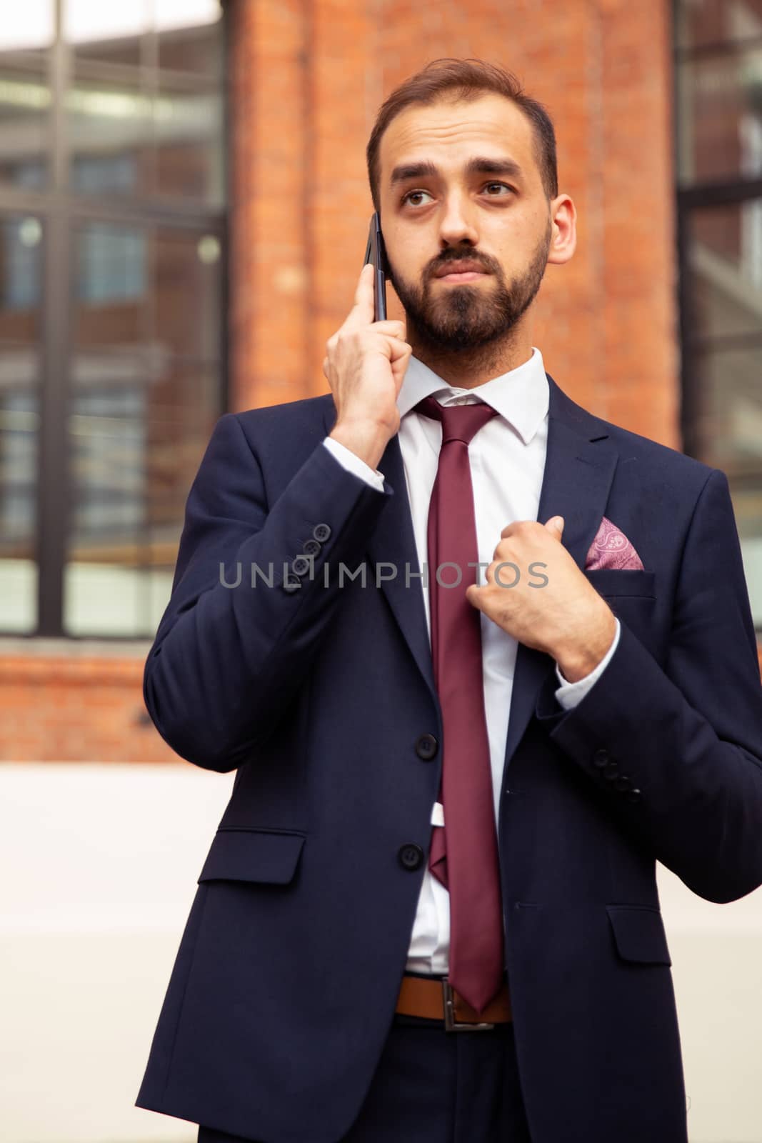 Business man talking on the phone and arranging his suit. Business style and professional attitude