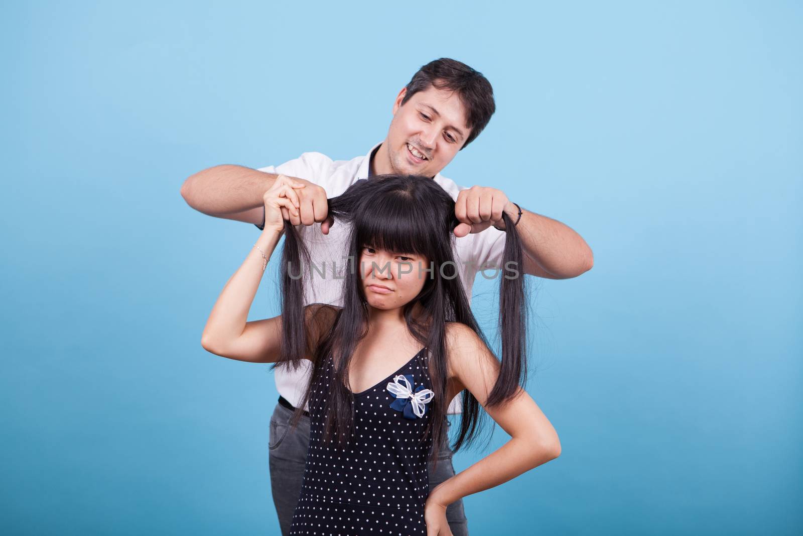 Caucasian boyfriend making fun of his asian girlfriend and pulling her hair. Interracial couple.