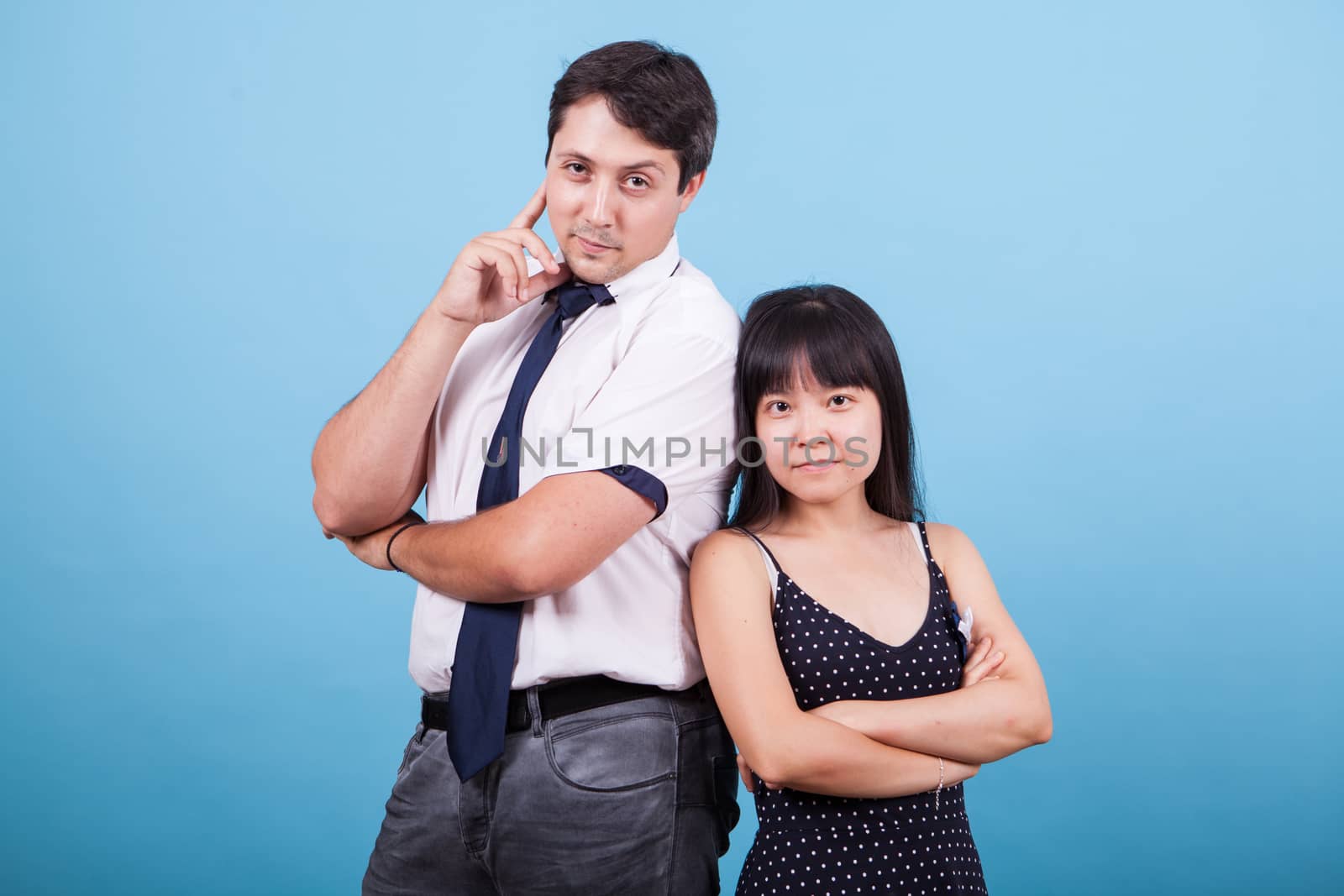 Cheerful young interracial couple looking at the camera in studio. Asian girlfriend.