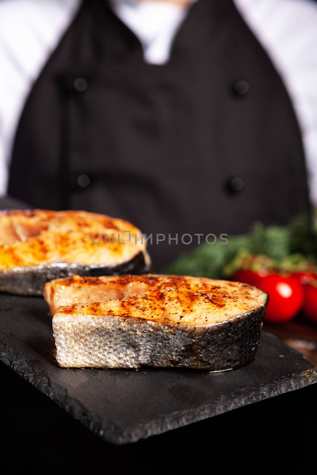 Close up of salmon rings with unrecognisable cook holding the countertops. Tasty fish