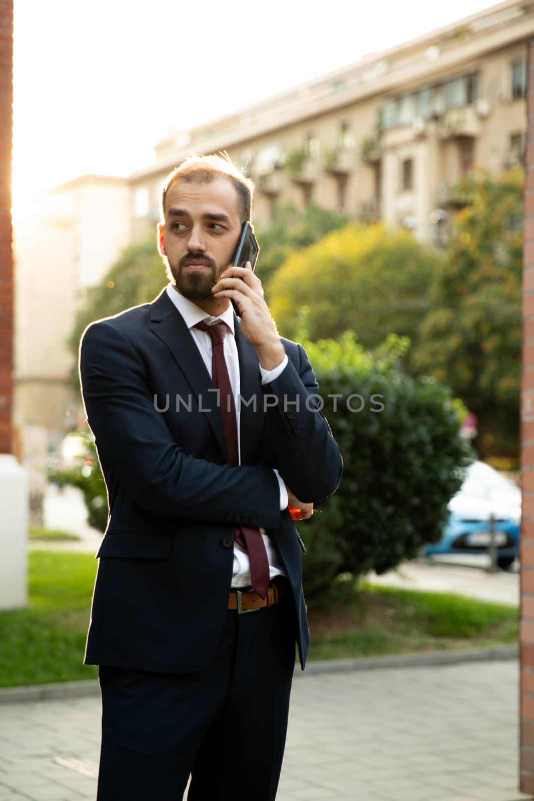 Successful businessman talking on the phone at sunset. Business style and street