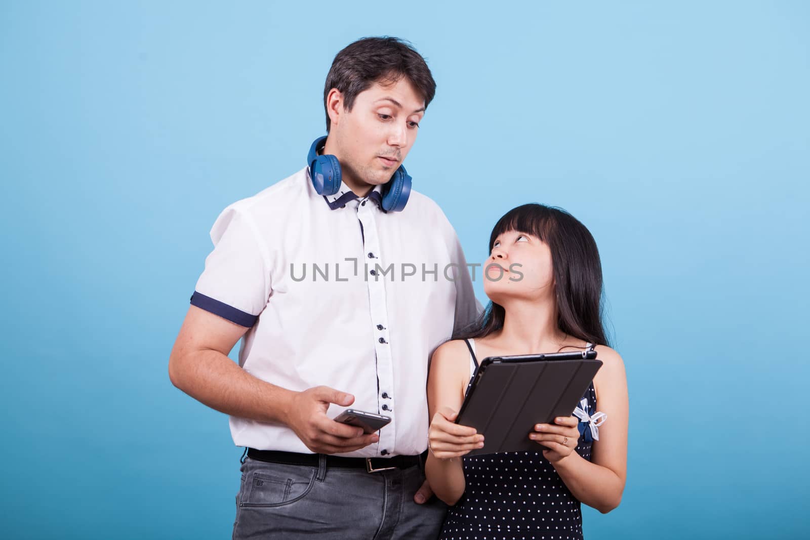 Asian girlfriend showing something on tablet to her caucasian boyfriend. Interracial couple.