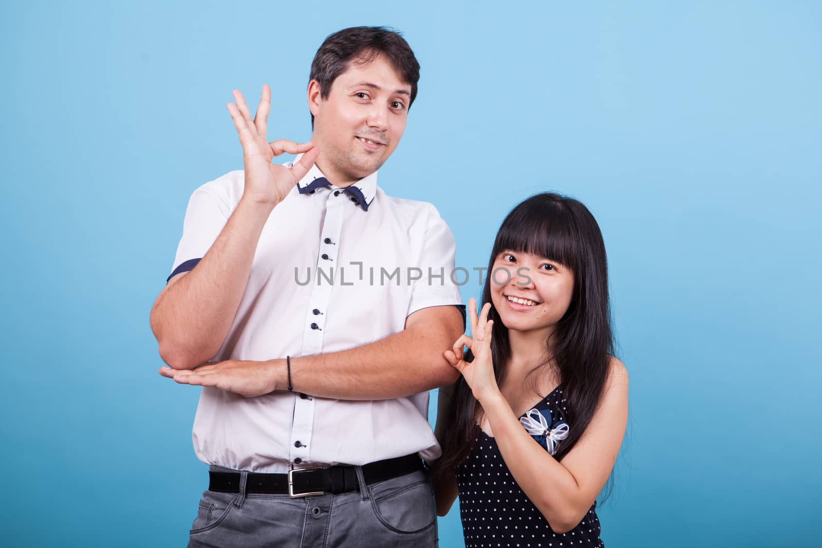 Smiling interracial couple showing ok hand gesture. Asian girlfriend.