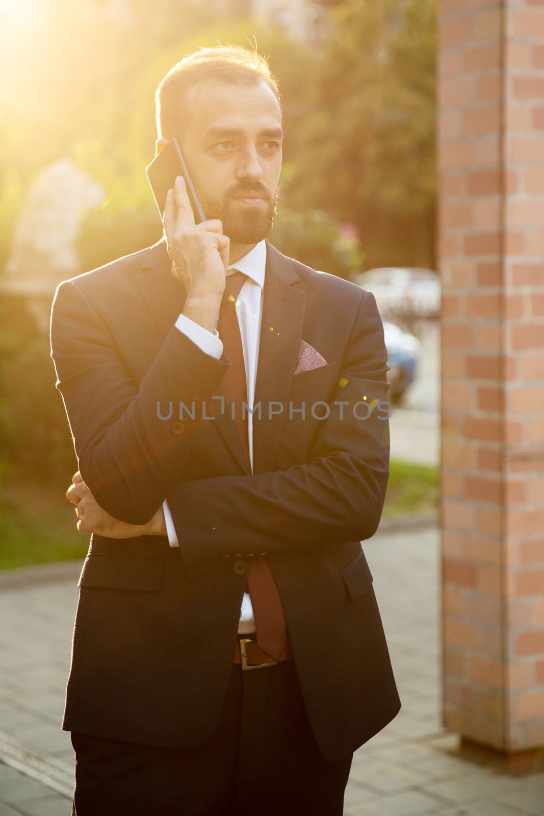 Businessman talking on the phone outside at sunset. Business on the go