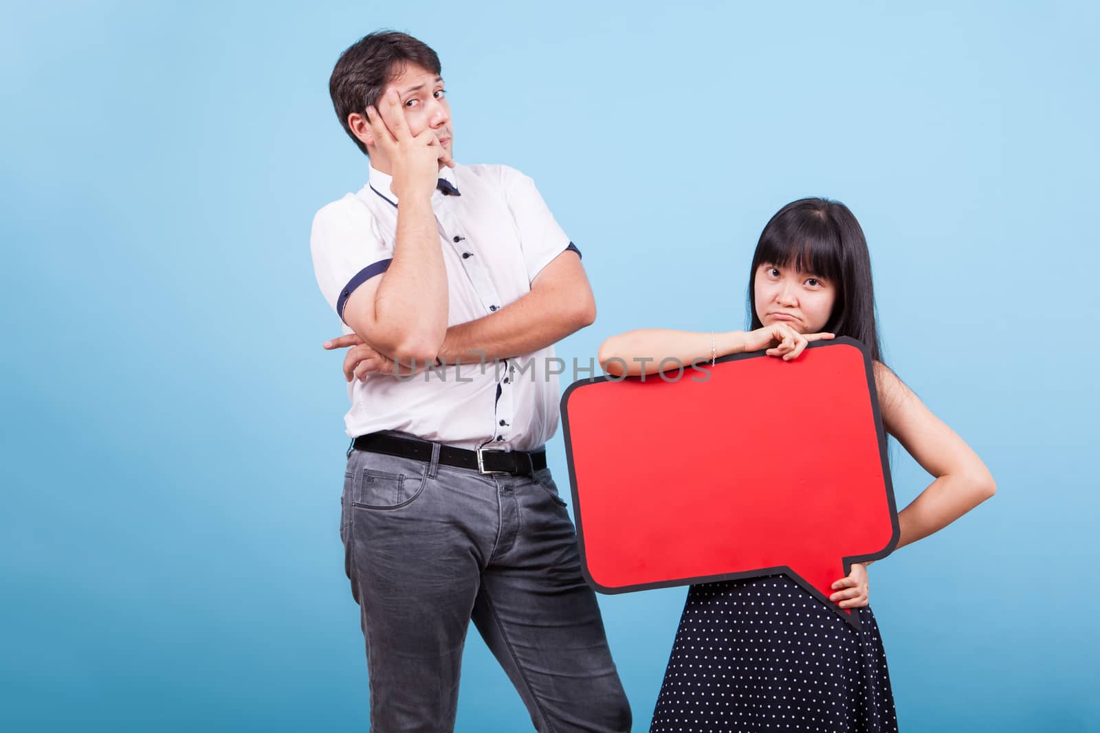 Thoughtful interracia couple looking at the camera in studio. Asian girl holding blank bubble thought.