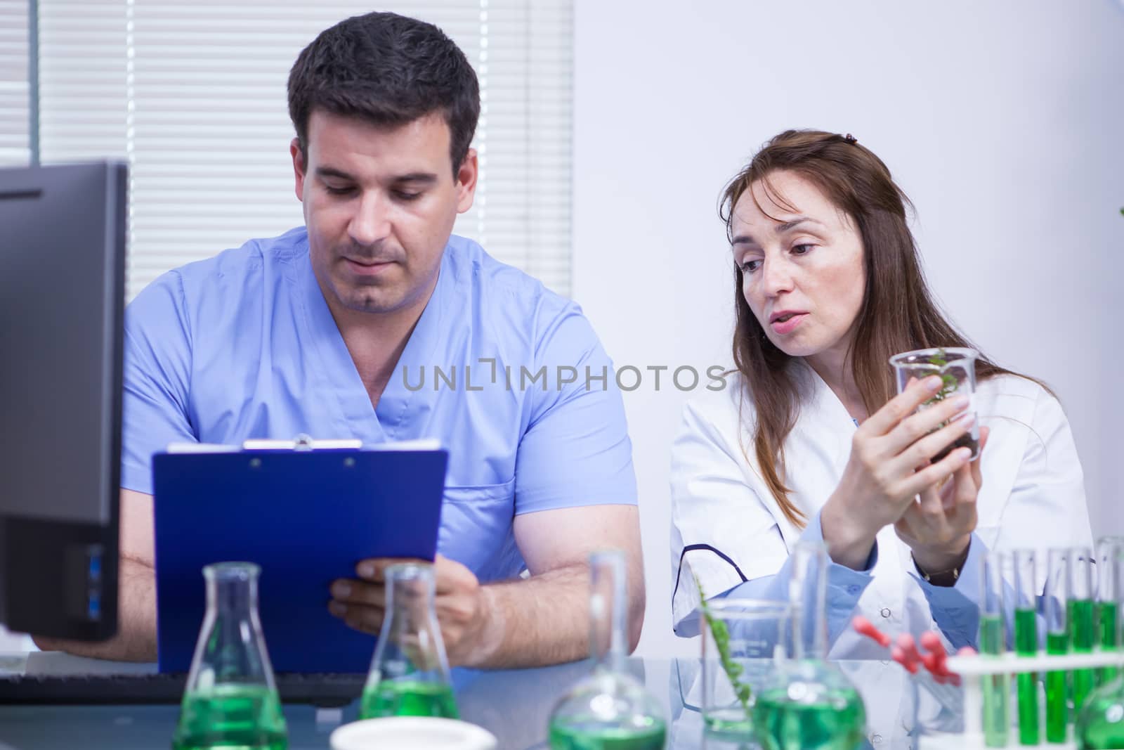 Young assistant writing notes on his notepad in a research lab. Female scientist.