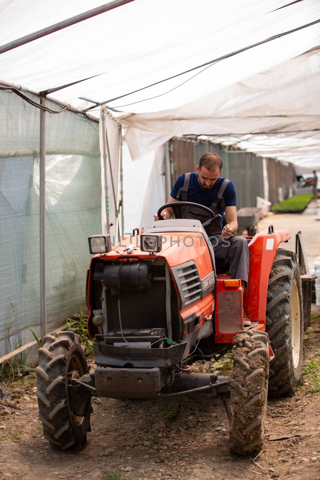 Worker trying to start a tractor at the greenhouse.