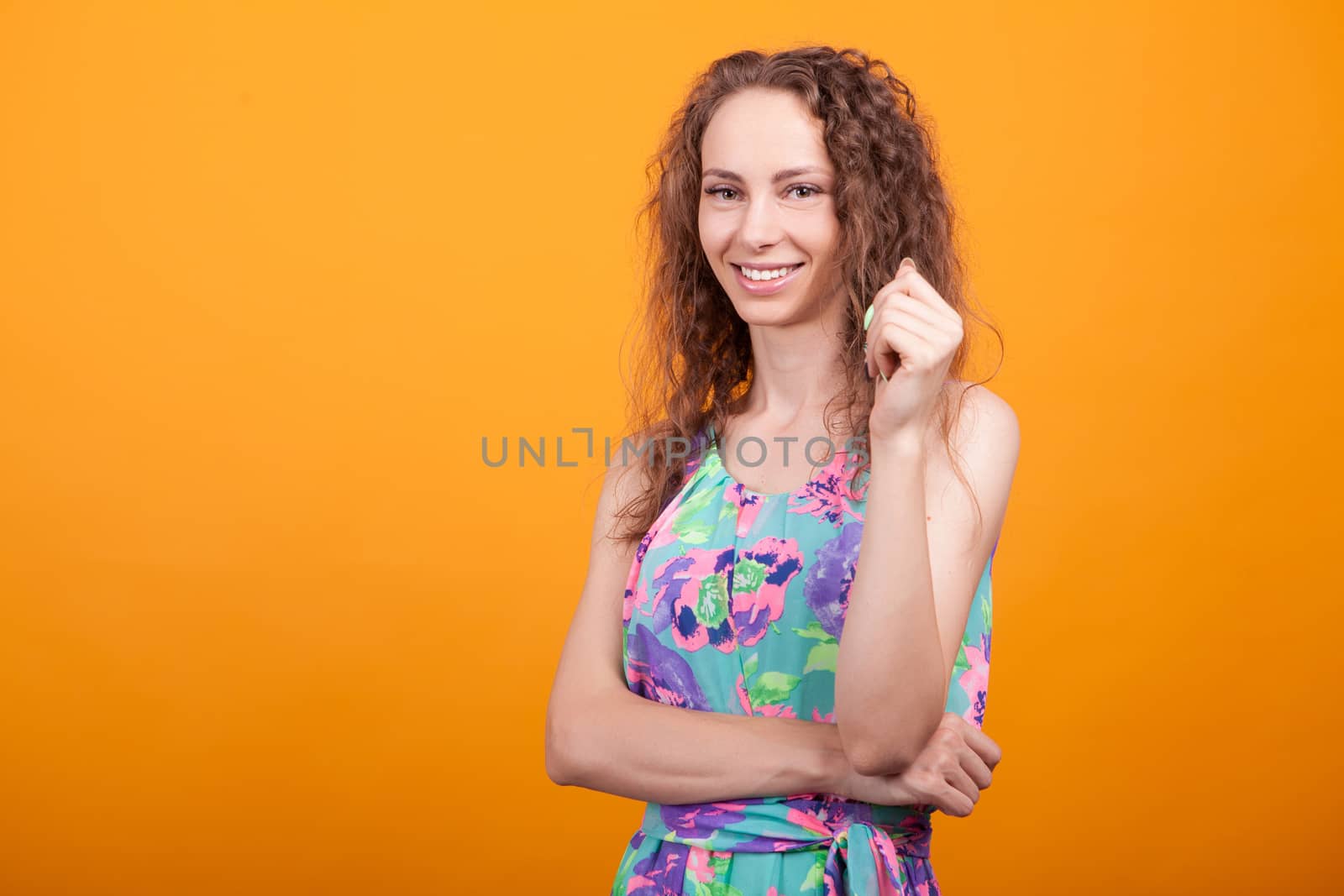 Caucasian woman with joyful expression in studio posing with arms crossed.