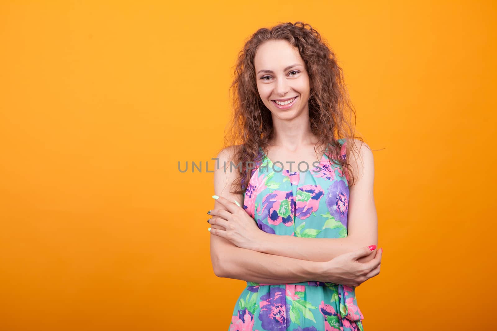 Cheerful young woman keeping her hands crossed and smiling in studio. Caucasian woman.