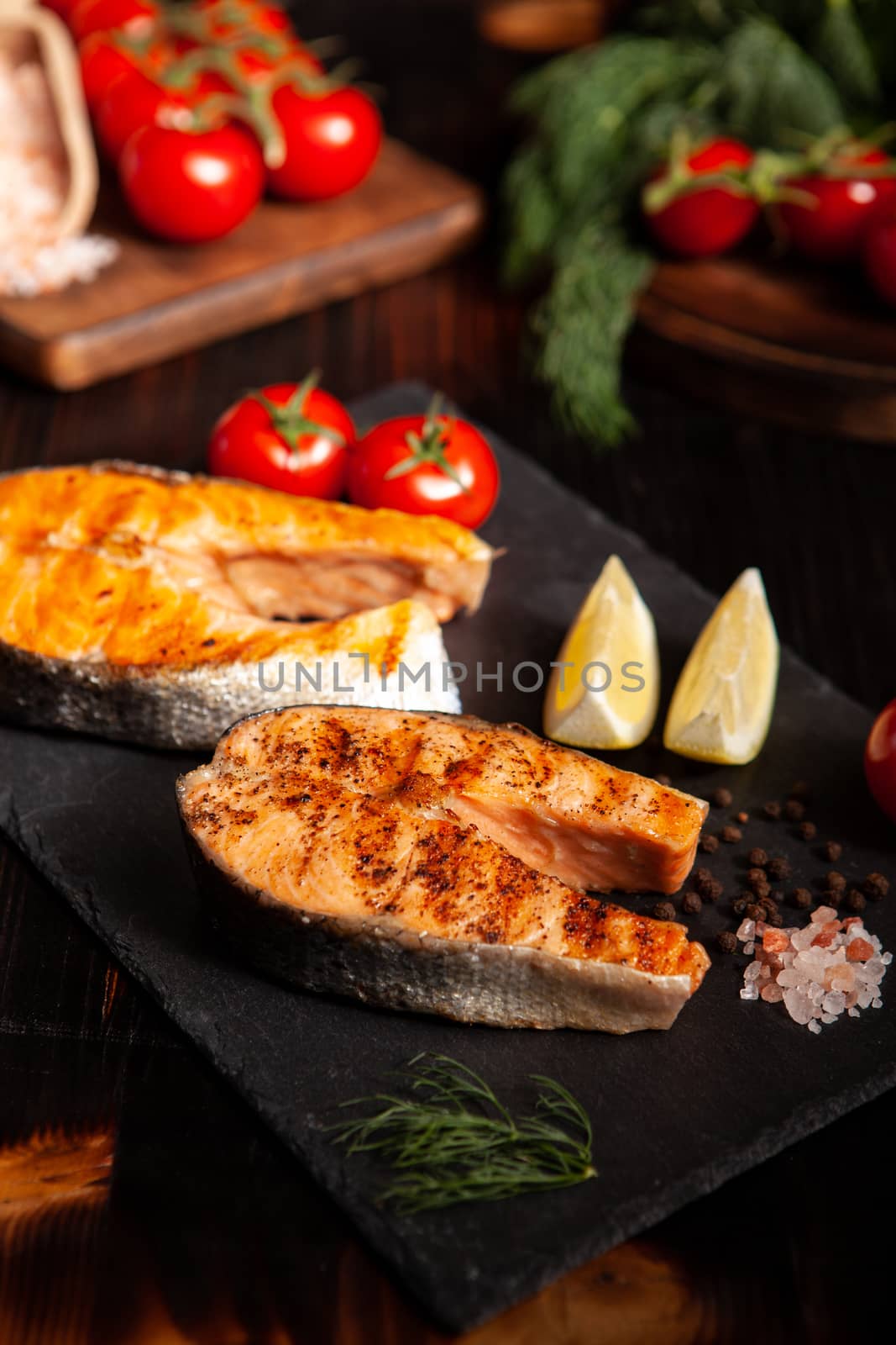 Cooked salmon rings carefully arranged on a platter. Lemon and tomatoes on the background