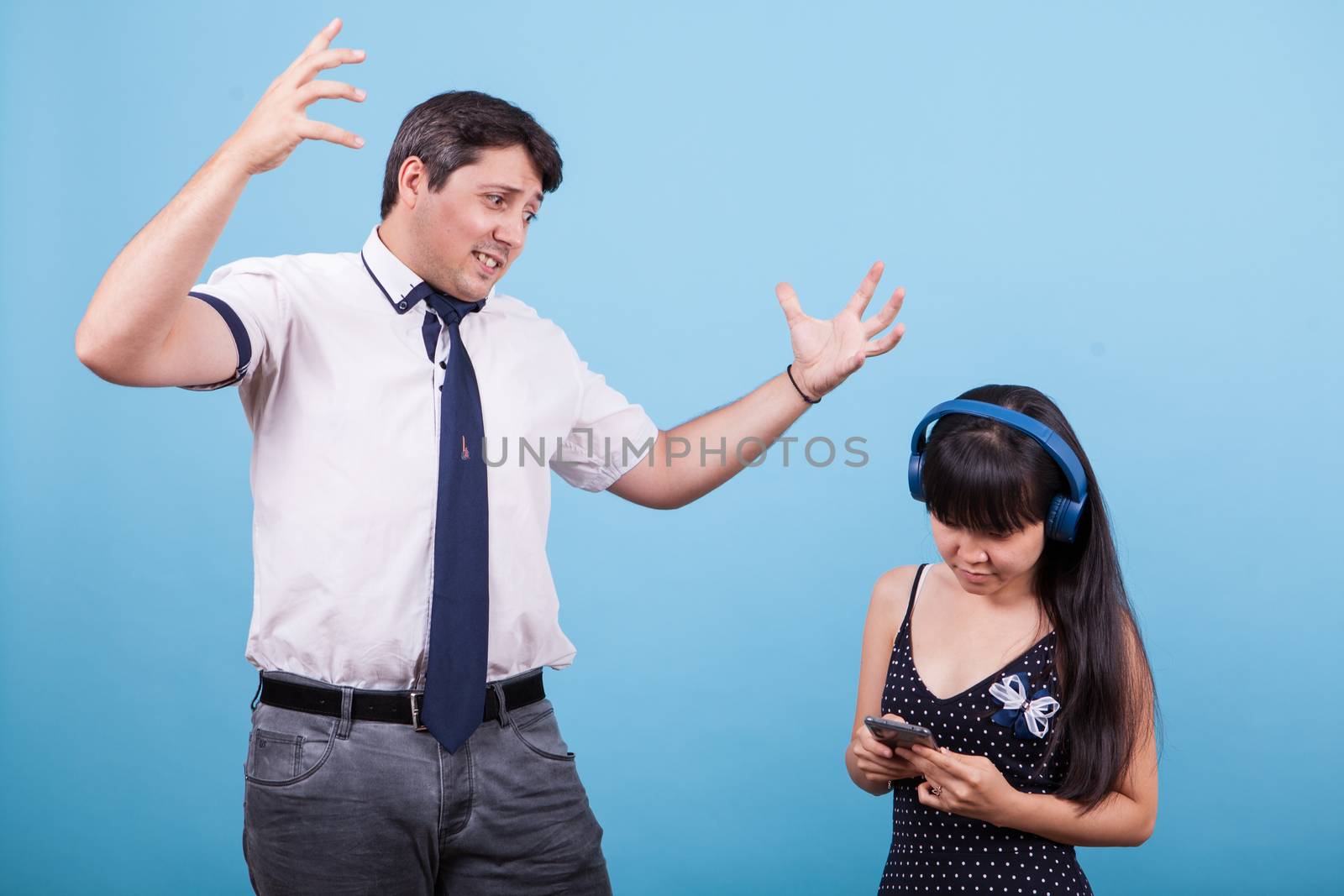 Angry caucasian man on his asian girlfriend for ignoring him. Interracial couple.