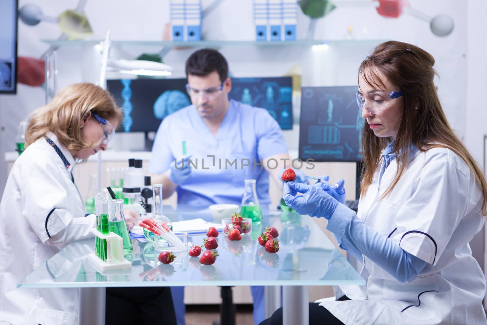 Team of reseach scientist in a lab doing analysis on strawberries. Modern technoloy in a lab research.