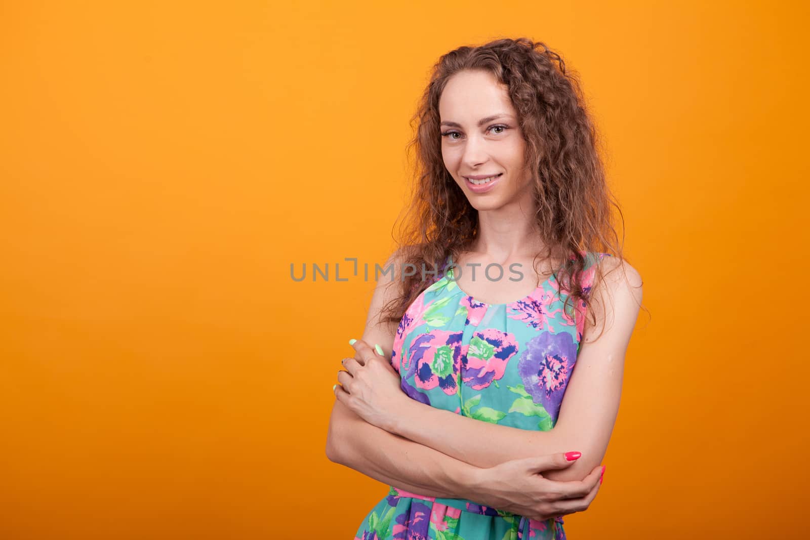 Portrait of beautiful woman with a big and natural smile in studio. Crossed arms.