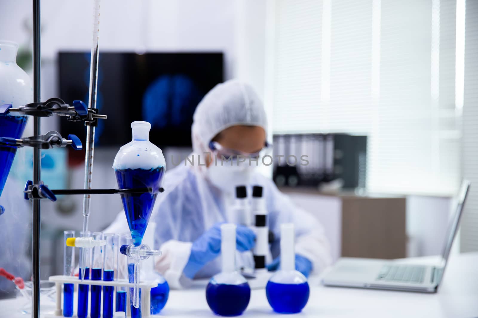 Close up of smoking blue solution in test tubes and scientist in the background working.