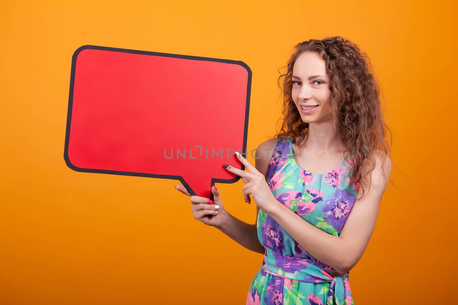 Caucasian woman holding on her right an empty bubble thought sign in studio over orange background.
