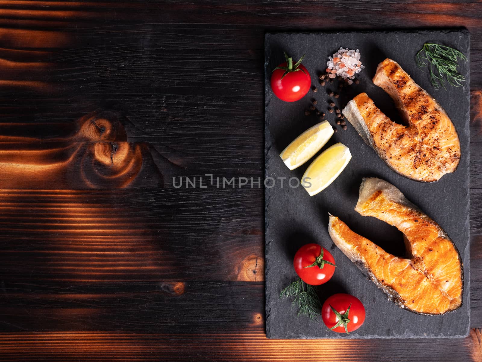 Top view with salmon rings arranged on a stone platter. Tomatoes and lemon