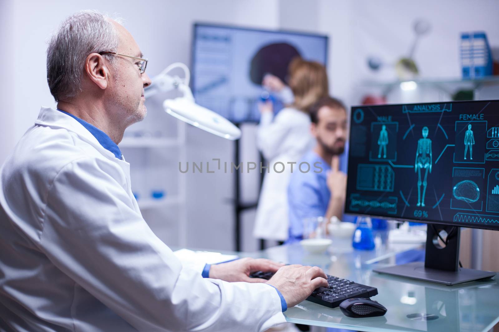 Experienced senior scientist typing the data in computer from last experiment on human body. Inovation center.