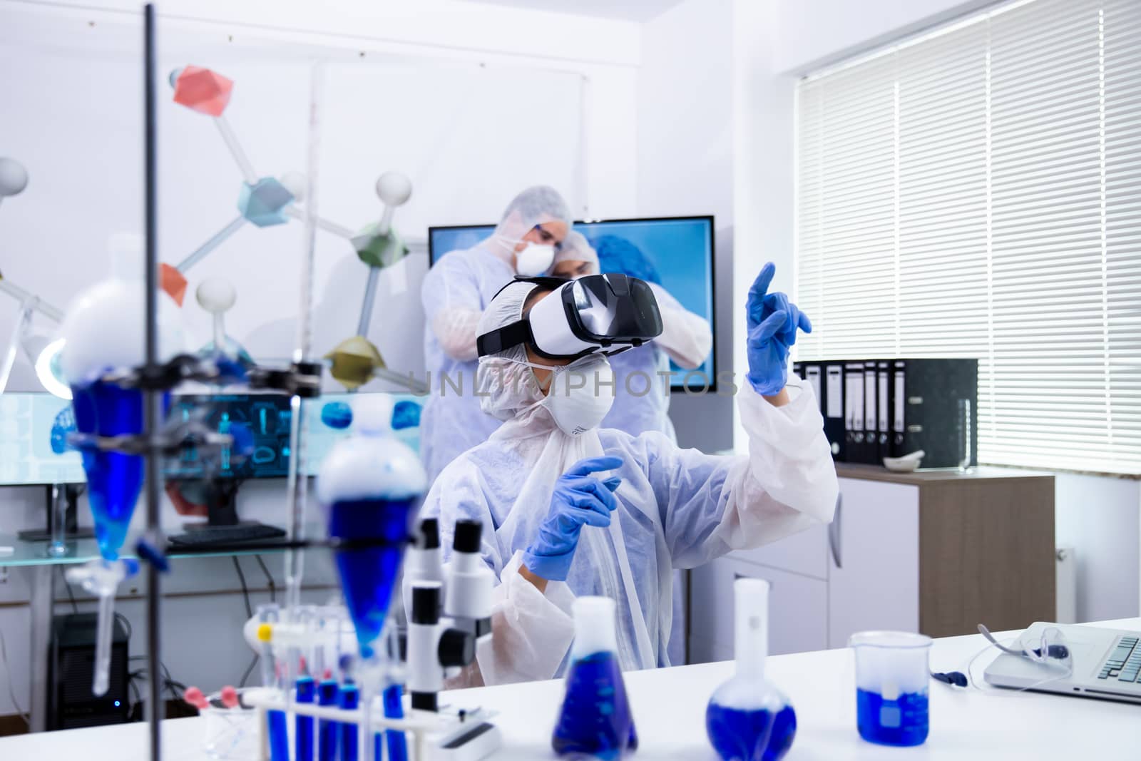 Female researcher using virtual reality goggles in her experimental test. Team of scientist in modern laboratory.